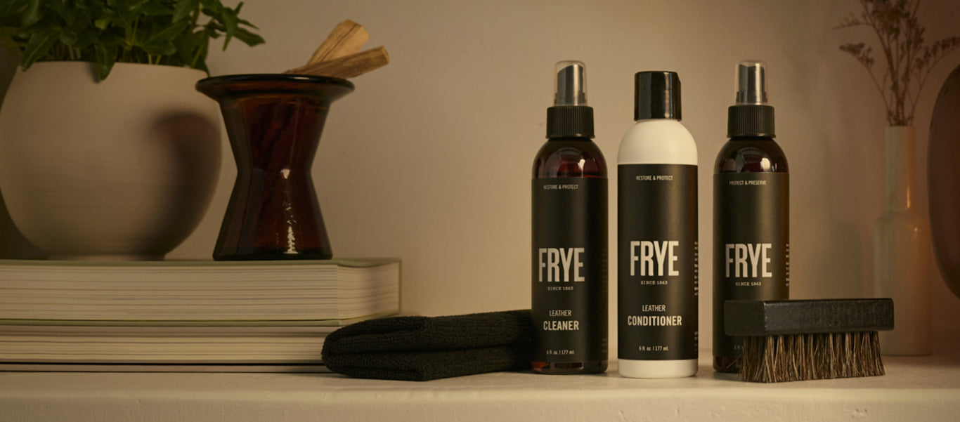Frye care products lineup with labels: Weatherproof Spray, Leather Conditioner, Suede Brush, Horsehair Brush, Refresher
